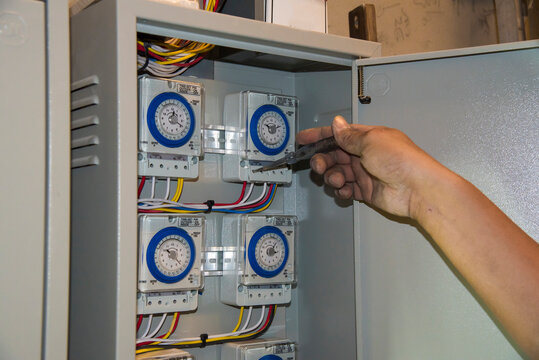 Engineer checking timer switch in electric control boxes
