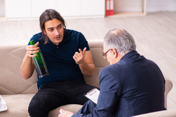 Alcohol addicted young man visiting old male psychologist
