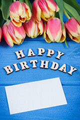 Inscription happy birthday and bouquet of tulips on boards. Surprise for birthday. Place for text on paper card