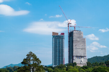 Tall buildings are building in the middle of trees, mountains, nature and beautiful sky.