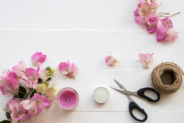 pink flowers bougainvillea ,rope ,scissors and candle arrangement flat lay postcard style on background white wooden