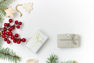 Christmas composition. Gifts, branches of blue spruce, wooden Christmas toys, red berries on a white background.