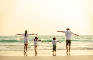 Happy Asian Family parents with two child boy and girl holding hands and walking together on the beach at summer sunset. Father, mother and kids enjoy and having fun in outdoor holiday vacation.