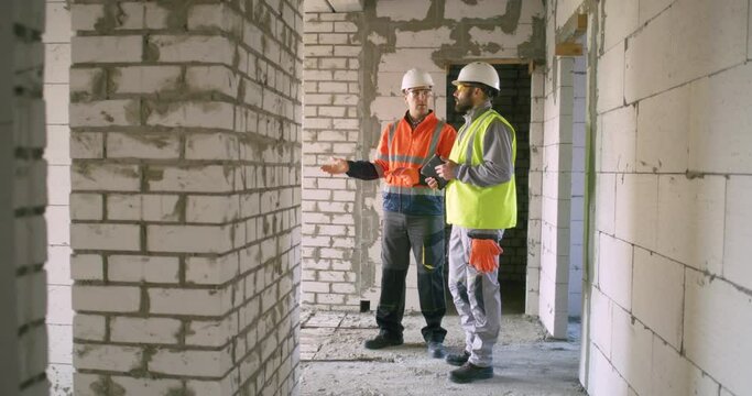 Foreman showing construction site to inspector with tablet