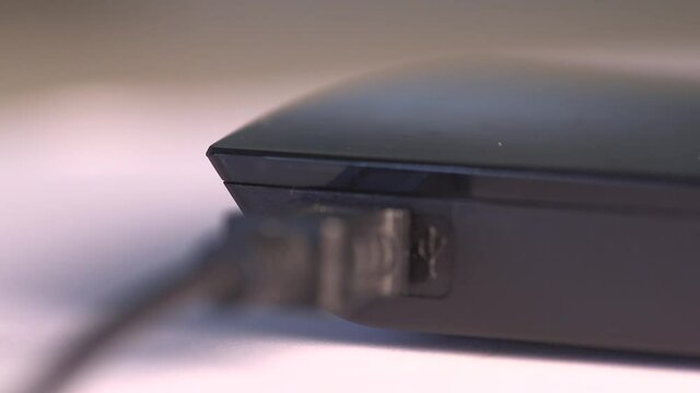 Close up of a man's hand plugging in an eternal hard drive.