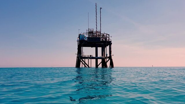 Sea level perspective of offshore oil platform or gas rig approach in open sea