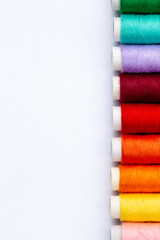 Colorful sewing threads on white background, top view. Spools of thread in different colors.