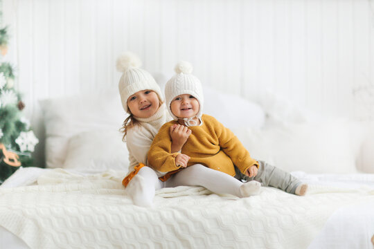 cozy New Year's children siblings in knitted hats and sweaters, gentle home photos of children, the concept of New Year and Christmas