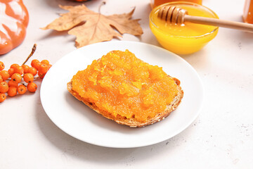 Plate with tasty bread and pumpkin jam on table