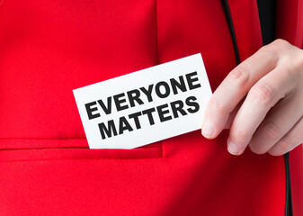 Businessman putting a card with text Everyone Matters in the pocket