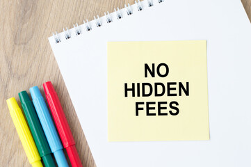 No hidden fees text on a notebook, next to the colored markers on the table.