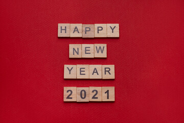 The inscription "happy New Year, 2021" made of wooden blocks on a red background 