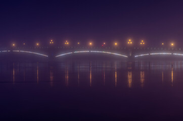Fototapeta na wymiar Foggy night landscape with Trinity Bridge with shining lanterns (Saint Petersburg, Russia)