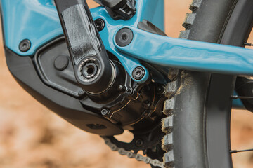 Details of electric mountain bicycle in blue color. Visible  electric motor hidden in bottom bracket.