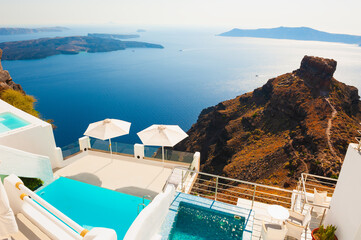 Fototapeta na wymiar White architecture on Santorini island, Greece. Swimming pool on the terrace with sea view. Beautiful seascape at sunset. Travel destinations concept