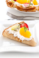 Crepes with soft cream, strawberries, kiwi, oranges and mint