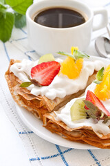 Crepes with soft cream, strawberries, kiwi, oranges and mint