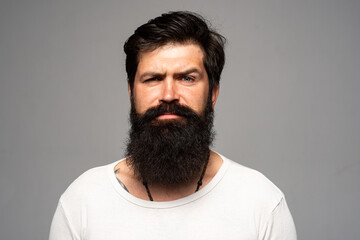 Obraz premium Portrait of confident serious man has beard and mustache, looks seriously, isolated. Hipster guy models in studio. Businessman thinking with expression looking. Handsome male model, closeup face.