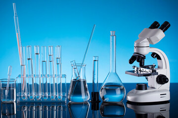 Science concept. Laboratory equipment composition. Test tubes and microscope on blue background.