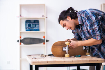 Young man repairing skateboard at workshop