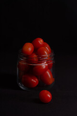 low key photo of cherry tomatoes in a glass jar isolated on black background
