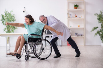 Young male patient in wheel-chair and experienced doctor traumatologist