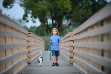 Kid taking a dog for a walk outdoors. Child with pet friend. Children little boy walks with the puppy.
