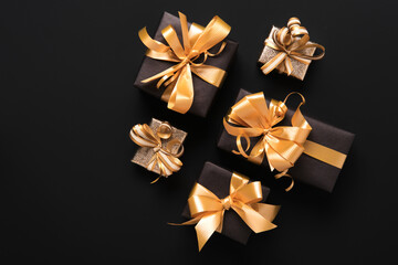 Festively wrapped golden gift boxes on black background. Flat lay style. Holiday and black friday concept