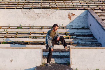 Tall handsome man on the crushed tribune of the old stadium