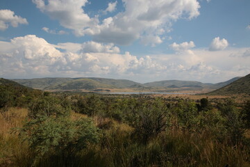 Fototapeta premium View of Pilanesberg National Park with mountains, grassland, bushland and lake during Spring in South Africa