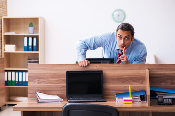 Young male employee in industrial espionage concept