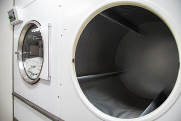 Big wide opening front doors of industrial dryer machines while the other is spinning. Shot taken...