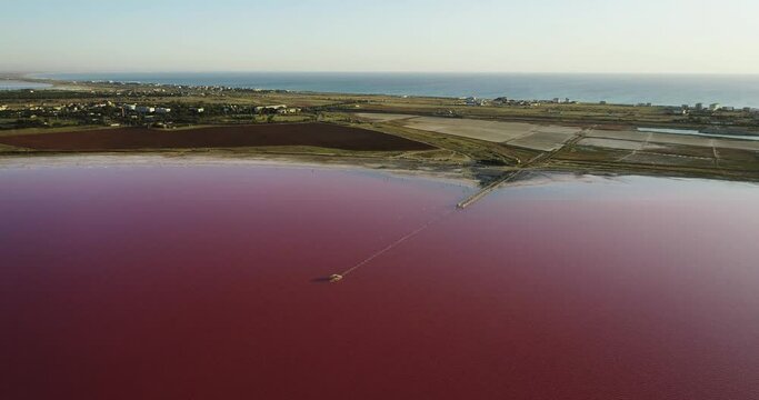 Pink saline sea with small wave / salt lake water evaporation ponds with pink plankton colour. Aerial top down wide shot at summer sunny day