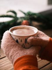 Closeup hands in mittens holding cup of hot chocolate. Christmas hot drink