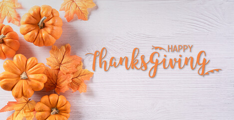 Thanksgiving background decoration from dry leaves and pumpkin on  wooden background. Flat lay, top view with Thanksgiving text.