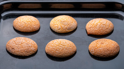 Delicate airy homemade sweet cookies in sugar glaze on a baking sheet.