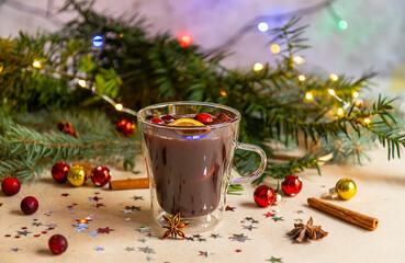 Glass with hot mulled wine and Christmas holiday decorations. 