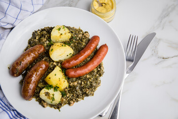 Oldenburger Grünkohl mit Pinkel, Kohlwurst, Senf und Kartoffeln auf Marmor Tisch