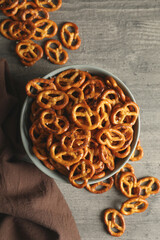 Bowl with tasty cracker pretzels on gray table