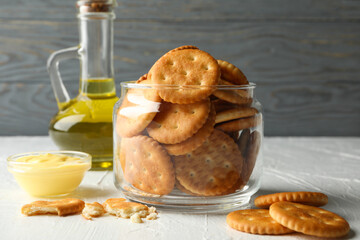 Glass jar with crackers, sauce and oil on white table