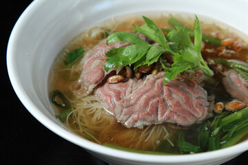 Bowl of beef noodle soup with meatballs and sliced beef; garlic cracklings with lard on top.