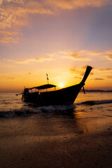 Traditional long-tail boat on the beach in Thailand at sunset - 389559529