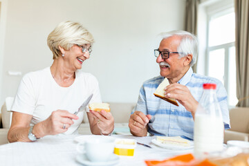 Senior couple making sandwiches for breakfast. Happy old couple communicating while enjoying in their breakfast. Elderly couple having fun.