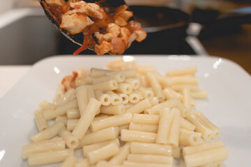Homemade pasta with tomato sauce in a white dish.