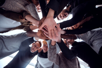 Obraz premium bottom view. group of happy young people making a tower out of their hands .