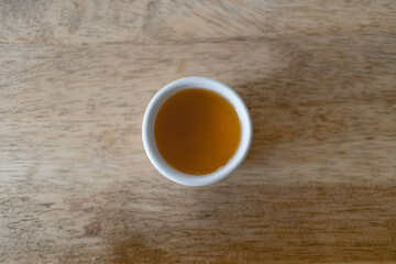 Closeup of hot tea in Chinese tea cup or Gaiwan on wooden table.
