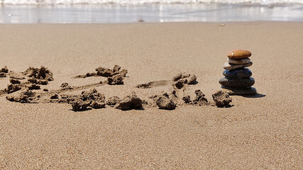 Fototapeta na wymiar zen stones laid out by hand lying on sand of sea beach