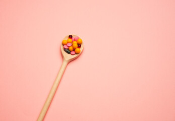 multi-colored tablets in a wooden spoon, concept