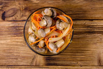 Canned mushrooms with carrot and onion in a ceramic bowl. Top view
