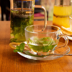 Transparent cup for tea with mint leaves and dried fruits on a wooden table. cafe concept
